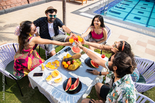 Sticker Group of indian friends toasting cocktail at outdoors summer party, Young multi ethnic people having fun together drinking juice enjoy fruits and snacks buffet, Vacation and holidays