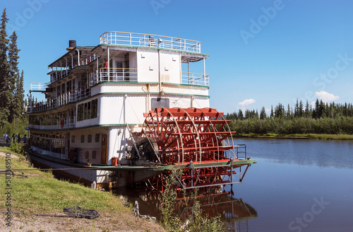 tourists boarding a sternwheel river boat to cruise the Chena River near Fairbanks in Alaska with the river and forest and blue sky in the background