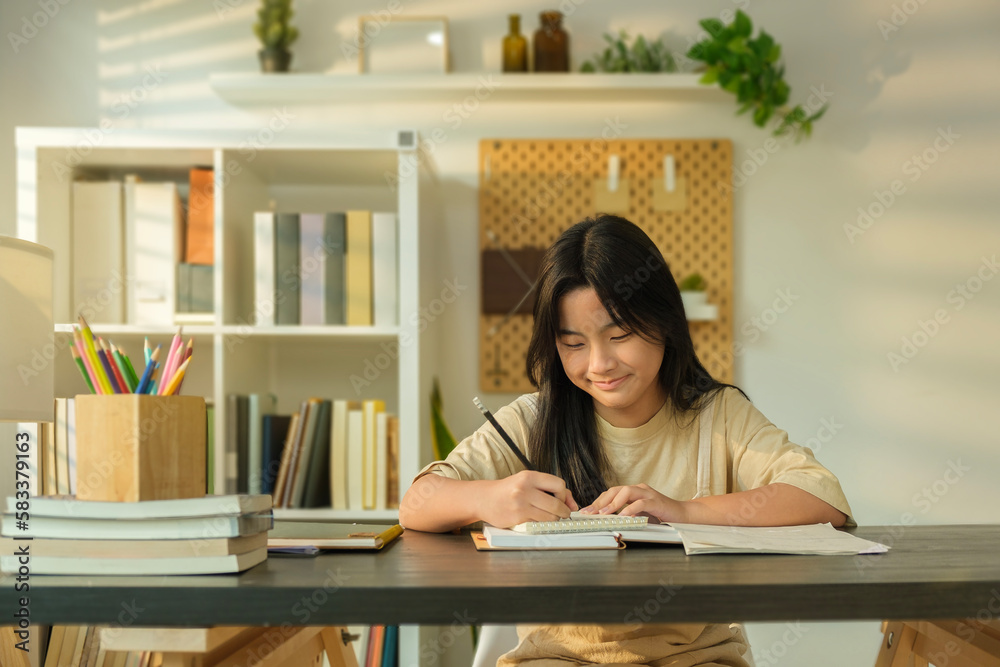 Smiling young female student writing on notebook, doing homework in cozy sunny living room. Educational concept. Smiling young female student writing on notebook, doing homework in cozy sunny living room. Educational concept.