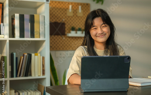 Portrait of smiling asian  girl using laptop, browsing internet, studying online at home.  Distance education and technology.