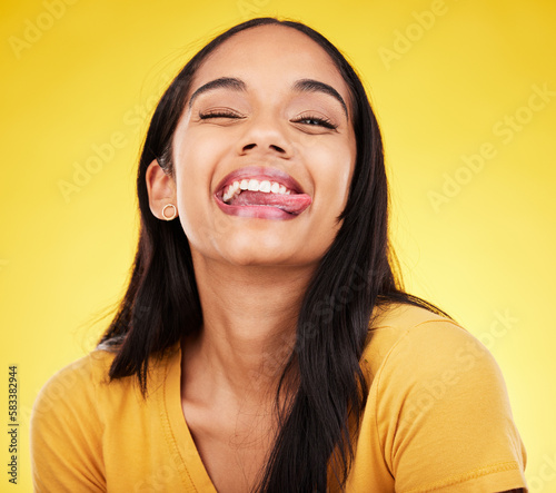 Woman, portrait smile and tongue out with silly facial expression against a yellow studio background. Happy, fun and goofy carefree female model smiling with teeth and funny face in joyful happiness