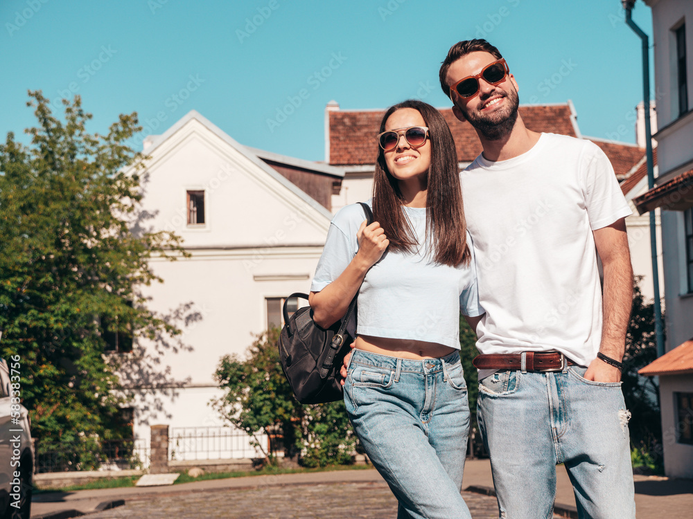Smiling beautiful woman and her handsome boyfriend. Woman in casual summer jeans clothes. Happy cheerful family. Female having fun. Sexy couple posing in the street at sunny day. In sunglasses