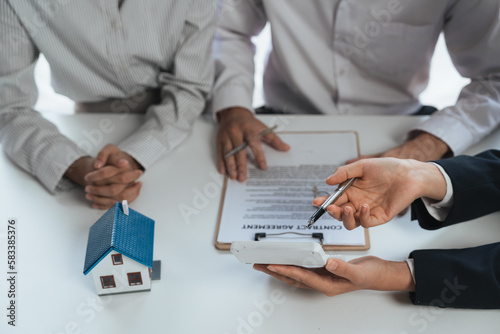 Fototapeta Naklejka Na Ścianę i Meble -  Happy couple signing a contract with real estate agent. renters tenants sign mortgage loan investment agreement or rental insurance contract meeting realtor lender landlord making real estate sale