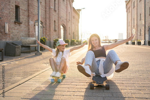 Mother and child spending their free time skateboarding outdoors. Happy family spending leisure time together. © Julija