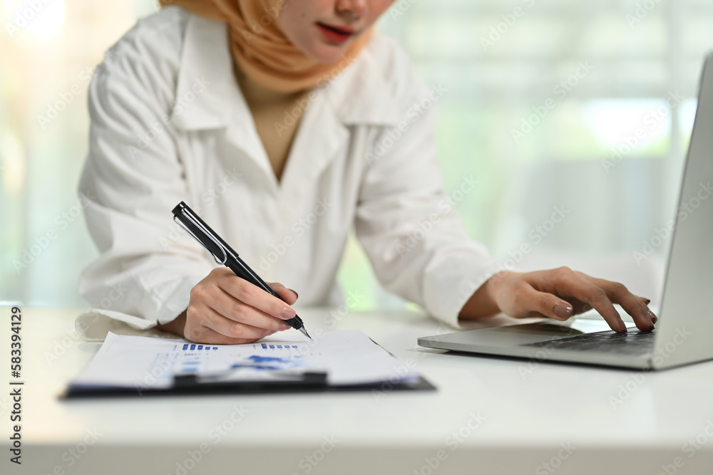 Muslim businesswoman using laptop computer and writing ideas or preparing for negotiations or seminar Muslim businesswoman using laptop computer and writing ideas or preparing for negotiations or seminar