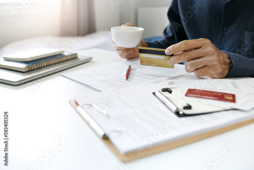 Asian businessman holding credit card and coffee cup checking order and invoice from online shopping, A man start new business online and using a credit card to pay for order