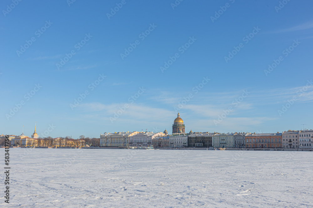 The urban landscape of St. Petersburg with a view of St. Isaac's Cathedral with a brilliant dome against the blue sky, view from the University embankment.