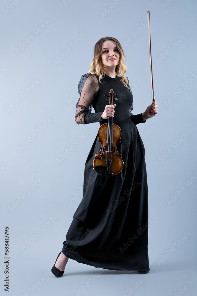 Violinist woman in the evening gown on the grey background. Violinist woman in the evening gown on the grey background.