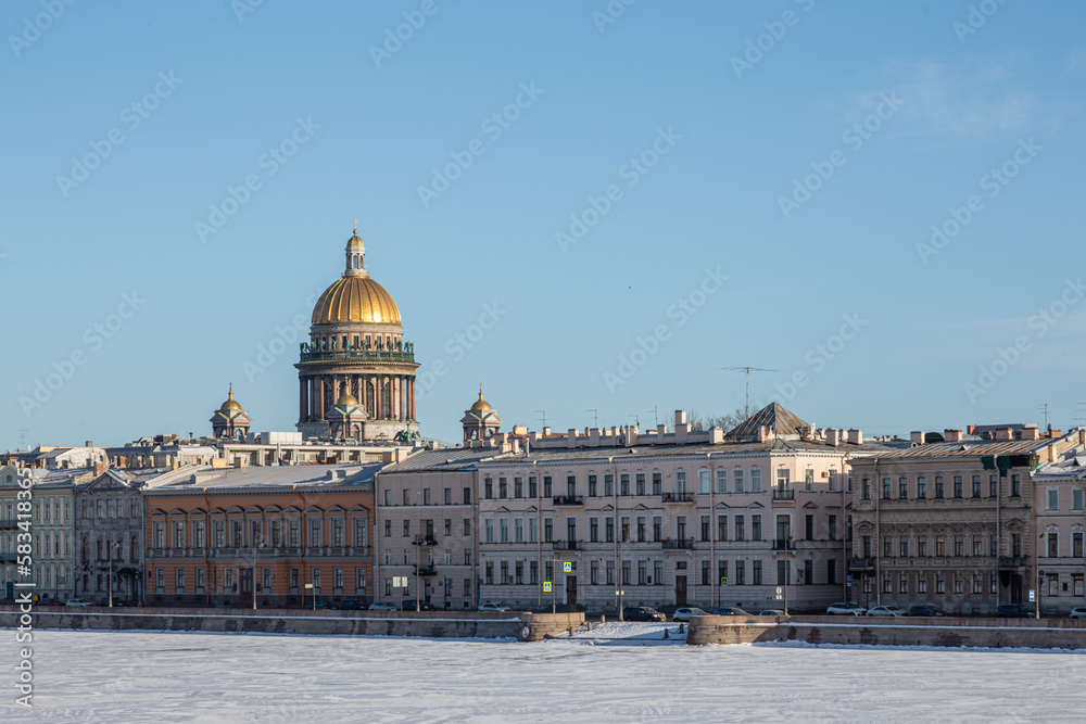 The urban landscape of St. Petersburg with a view of St. Isaac's Cathedral with a brilliant dome against the blue sky, view from the University embankment.