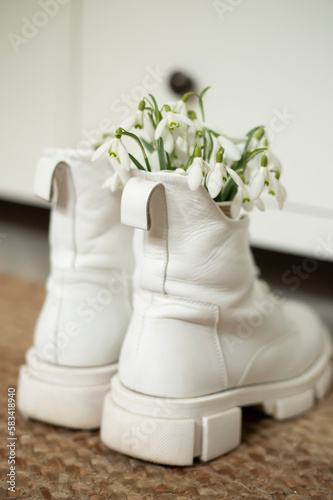 Artistic composition with white boots and a bouquet of snowdrops