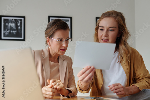 Cuadro en lienzo Young blond female worker of art gallery showing photo to mature colleague while