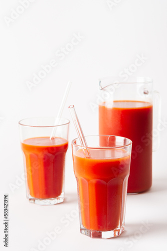 Homemade freshly squeezed tomato juice in glasses and a jug on a white background
