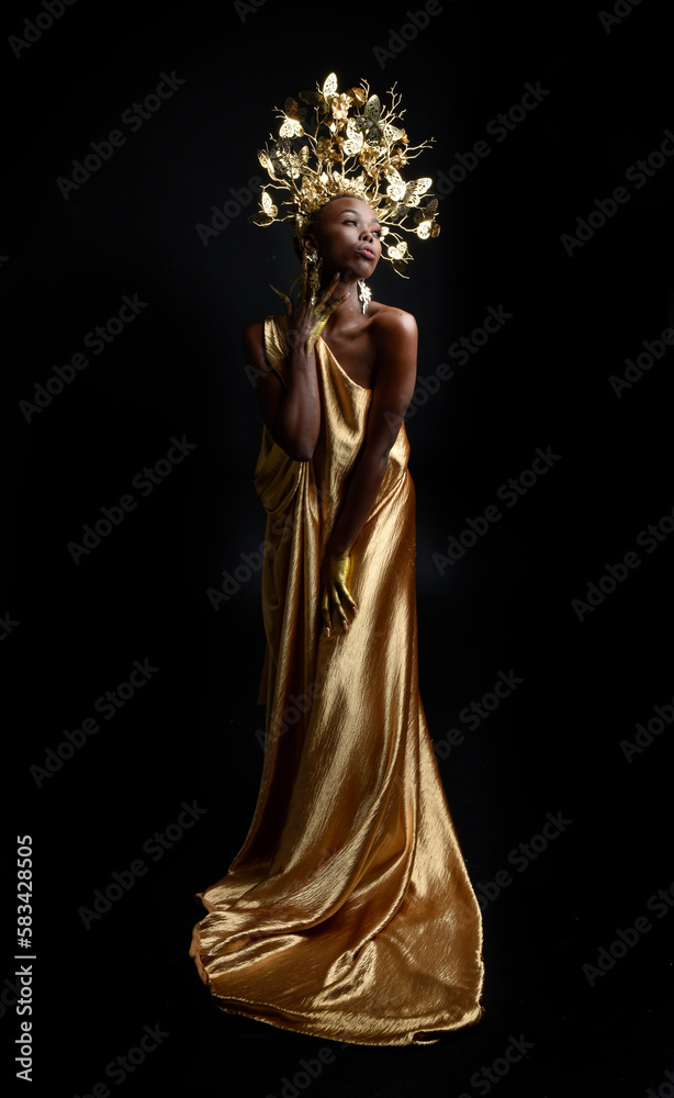  fantasy portrait of beautiful african woman model with afro, goddess silk robes and ornate floral wreath crown. gestural Posing holding golden flowers. isolated on dark  studio background 