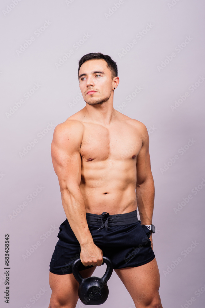 Strong young muscular focused fit man with big muscles holding heavy kettlebells Strong young muscular focused fit man with big muscles holding heavy kettlebells