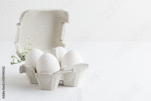 White eggs in a eggbox standing on a white table photo