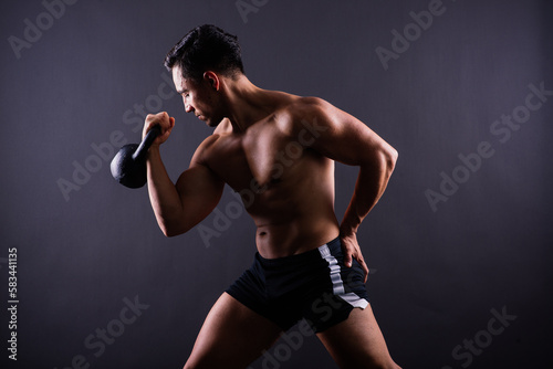 Strong young muscular focused fit man with big muscles holding heavy kettlebells © Ivan Zelenin