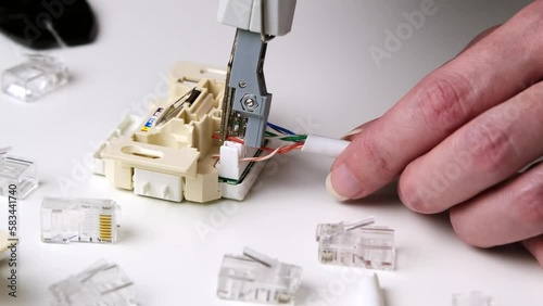 a worker crimping a network cable for an RJ45 module into a ethernet socket. photo