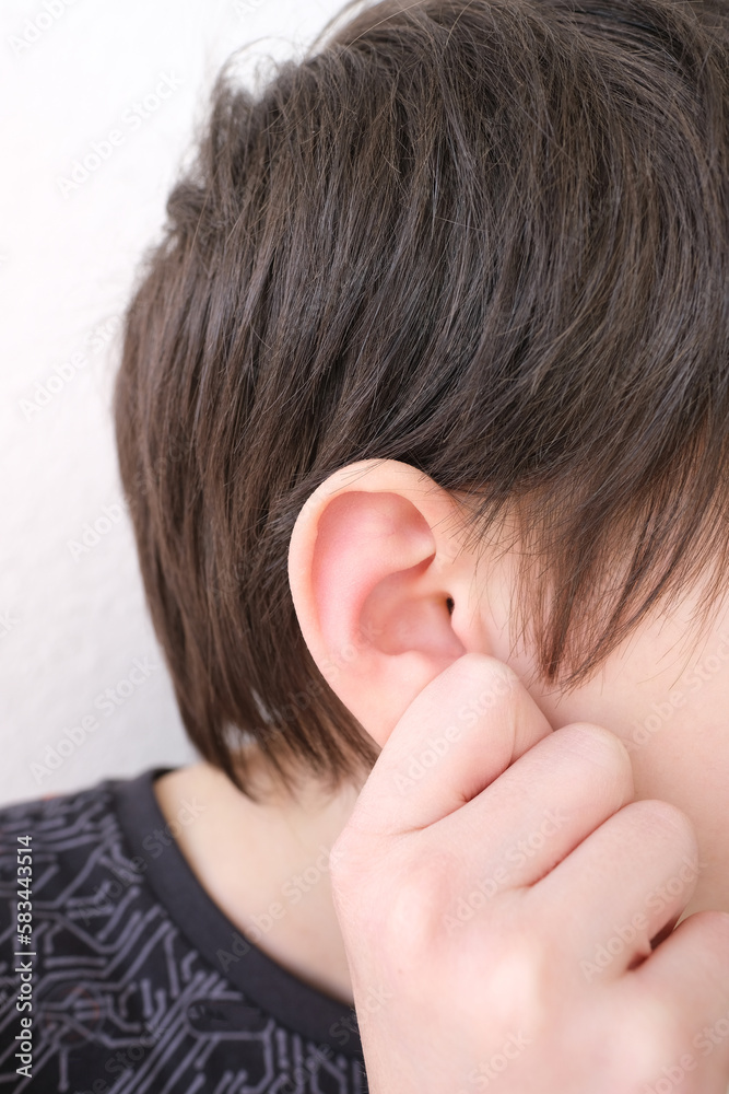 part of child's face in profile, a boy of 10 years old touches sore ear, concept of hearing organs health, happy childhood, prevention of otitis media and hearing loss, World Hearing Day