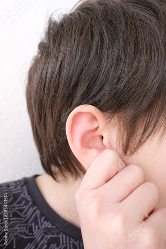 part of child's face in profile, a boy of 10 years old touches sore ear, concept of hearing organs health, happy childhood, prevention of otitis media and hearing loss, World Hearing Day