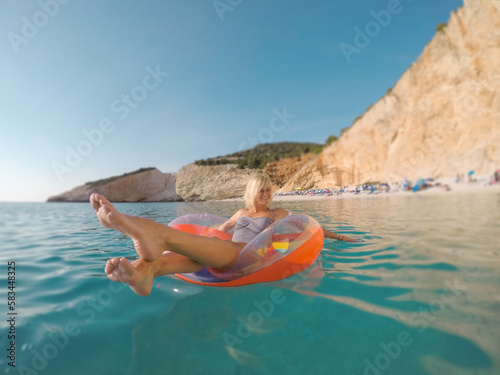 Beautiful woman swimming on the inflatable ring in the sea on Porto Katsiki beach.