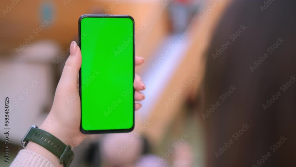 Use green screen for copy space closeup. Chroma key mock-up on smartphone in hand. Woman holds mobile phone and swipes photos or pictures left indoors of cozy home 4K Use green screen for copy space closeup. Chroma key mock-up on smartphone in hand. Woman holds mobile phone and swipes photos or pictures left indoors of cozy home 4K