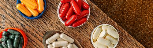 pills banner top view. multivitamin dietary supplements on a wooden desk. mental wellbeing and personal health concept