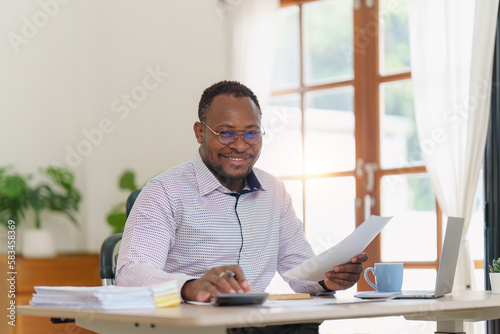 Smiling American African makes financial report and studies annual figures, analyzes profits. Accountant checks status of financial