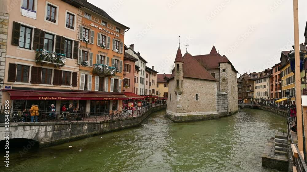 Annecy,France.January 2023.Enchanting glimpse of the historic center with the ancient prison in the middle of the water.The houses with colorful facades overlook the canal. People walk along the canal Annecy,France.January 2023.Enchanting glimpse of the historic center with the ancient prison in the middle of the water.The houses with colorful facades overlook the canal. People walk along the canal