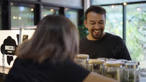 Slowmo of a male client talking to the retailer in a weed dispensary having fun photo