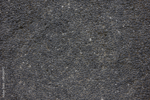 Texture of dark gray rough asphalt made of small stones. Solid dark black background.