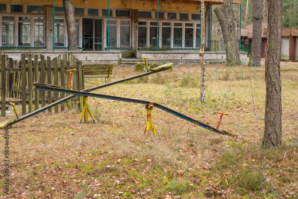 An old, dilapidated children's swing in an abandoned and forgotten holiday resort in the forest. Urbex. An old, dilapidated children's swing in an abandoned and forgotten holiday resort in the forest. Urbex.