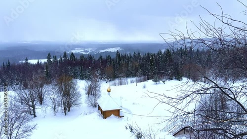 View of the chapel near the Belogorsky St. Nicholas Orthodox Missionary Monastery. Winter forest. The temple on the hill in winter. Russia, Perm Krai, Belaya Gora. 4K photo