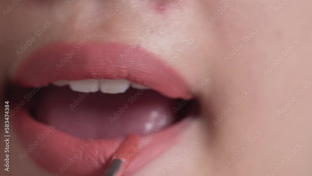 Closeup shot of woman paints her lips with lipstick.

