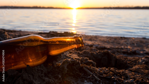 bottle on the background of the sea or river. soft focus at sunset. problems of environmental pollution