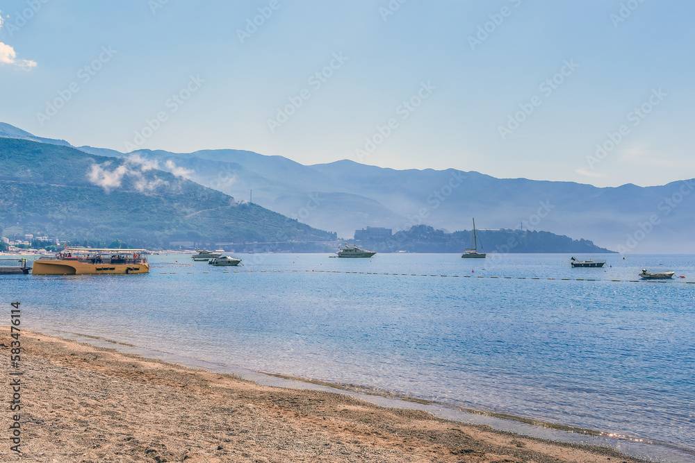 View from Slovenska Plaza beach on Budva Bay Plicina Tunjaj in Montenegro. Seascape with many boats and yachts in the water against the backdrop of mountains on a summer morning