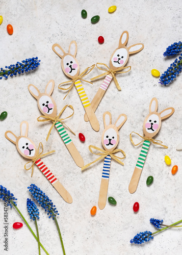 Topf view of handmade cute colorful rabbits made from wooden spoons. Small gift or decor for Easter. Easy fun kids crafts concept. Selective focus. Copy space.