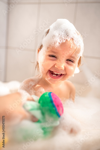 
a small child bathes in the bath. A child bathes with foam. Happy child bathing