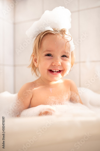 
a small child bathes in the bath. A child bathes with foam. Happy child bathing
