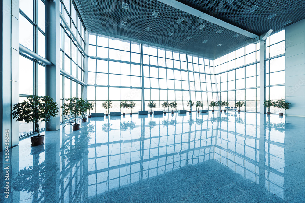 Interior of the modern lobby with glass walls and reflective floor, natural light