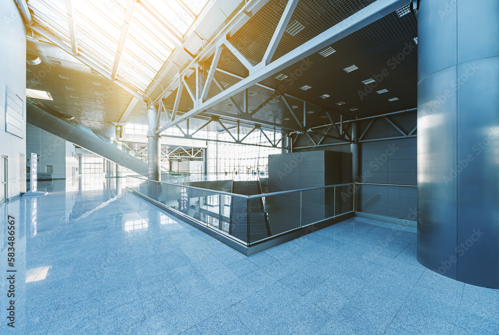 Corridor in the modern office building, with escalators, stairs, glass walls and reflective floor, natural light and flare