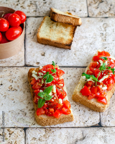 bruschetta with tomatoes, herbs and cheese on a stone surface, sandwiches with toasted bread and tomatoes for breakfast, snack