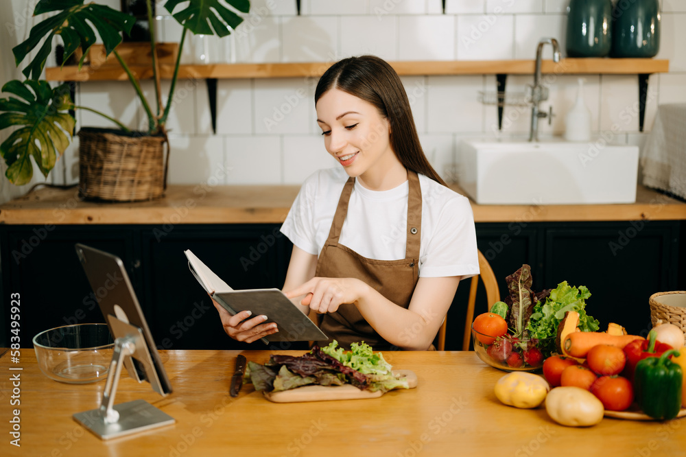 Young American woman learning online cooking class via tablet computer in kitchen