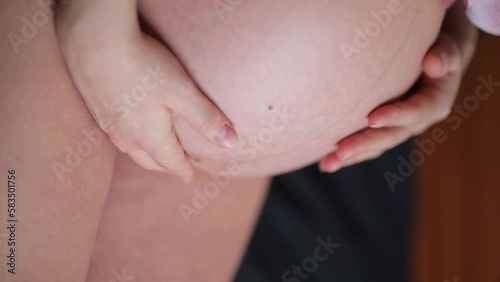 Wallpaper Mural A pregnant Caucasian woman is expecting a baby. A pregnant woman feels happy while stroking her baby in her belly. A pregnant woman is stroking her big belly on the bed at home. Vertical video Torontodigital.ca