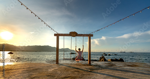 A female tourist relaxes on a swing at a tropical beach at 4-star Hon Co Resort, Ca Na in Ninh province. Thuan, Vietnam. She feels comfortable and happy with the scenery here