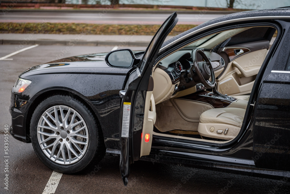 Side view of the open driver's door, mirror, dashboard of the car. Left front door. A new modern shiny parked black car. Interior luxury car with tinted glass standing at parking. Modern car exterior. Side view of the open driver's door, mirror, dashboard of the car. Left front door. A new modern shiny parked black car. Interior luxury car with tinted glass standing at parking. Modern car exterior.