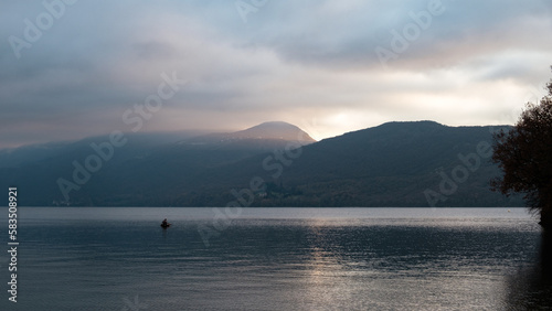Fisherman in his boat fishing on a Lake over the mountains, at sunset © Gnac49