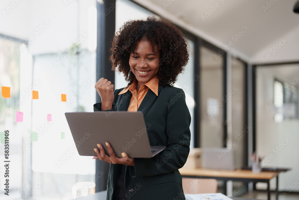 Beautiful young teen American African business women holding computer laptop with hands up in winner is gesture, Happy to be successful celebrating achievement success Beautiful young teen American African business women holding computer laptop with hands up in winner is gesture, Happy to be successful celebrating achievement success