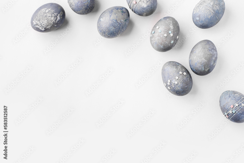 Festive Easter background. Gray-blue Easter eggs with stars on a white table. Greeting card with a place for text. Top view. Festive Easter background. Gray-blue Easter eggs with stars on a white table. Greeting card with a place for text. Top view.