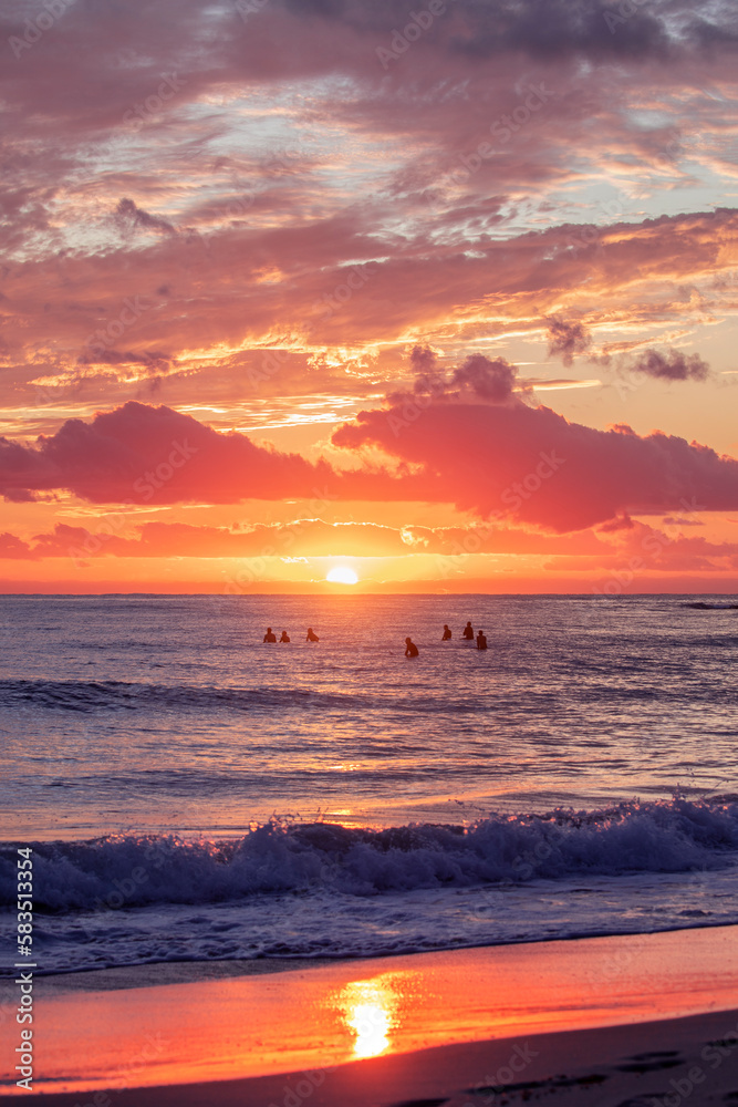 Fototapeta premium Beach view with surfers in the ocean at sunrise. Gold Coast, Australia