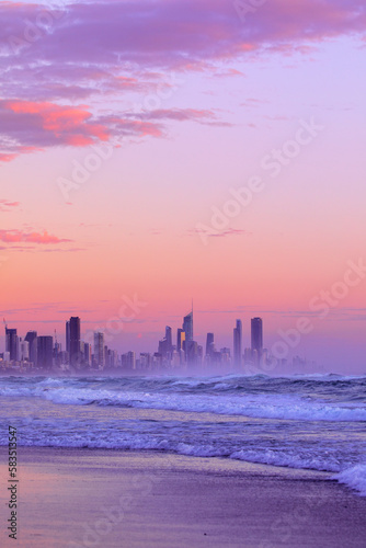 Beach view with golden sunrise skies with ocean waves, over Gold Coast cityscape